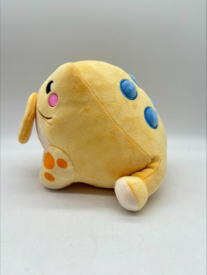 Lucky the Jin Chan plush by TOTYM, Chinese money frog from folklore, yellow‑orange with blue spots, holding a coin in its mouth, facing left on a clean white background.